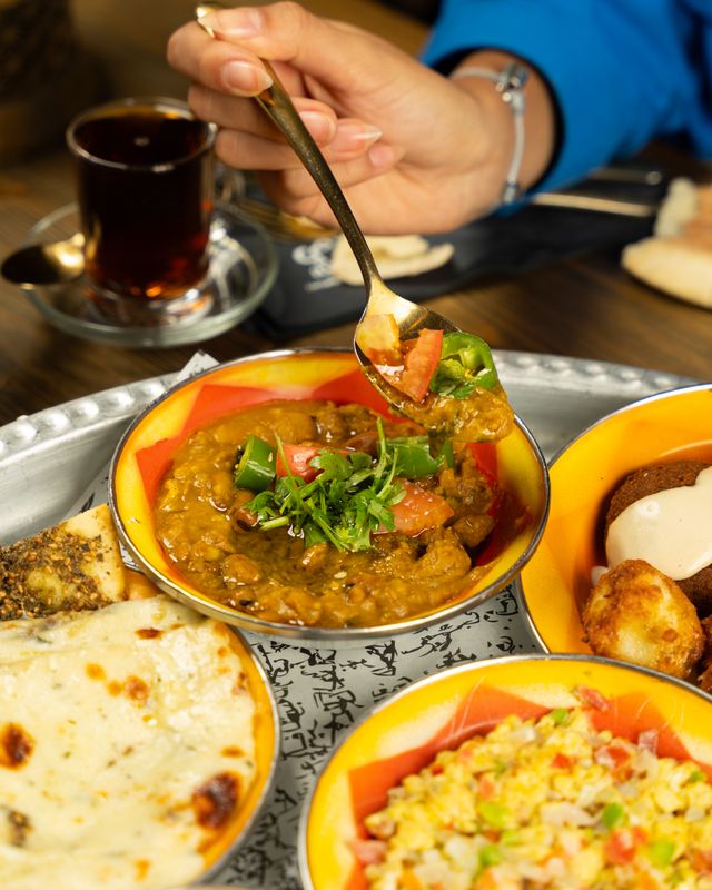 Family sharing authentic Indian food including Butter Chicken, Chicken Biryani, Garlic Naan, and Vegetable Samosas at The Royal Spice Indian Restaurant